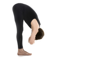 Profile of sporty young man on white background in uttanasana with elbow grab (intense stretch pose, forward bend, forward fold, head to knees), surya namaskar, sun salutation complex