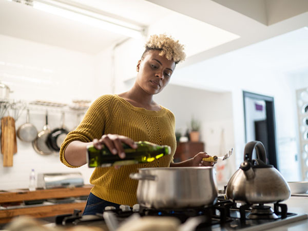 年轻女子在厨房里用橄榄油做饭