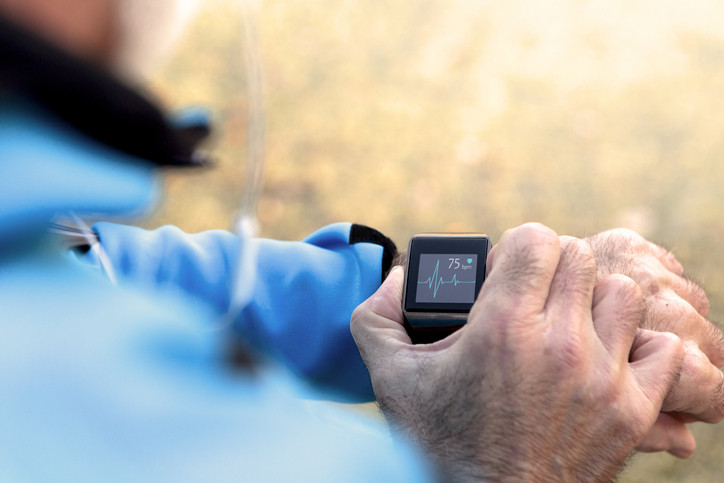 Elderly Man using Smart Watch measuring heart rate during walk.