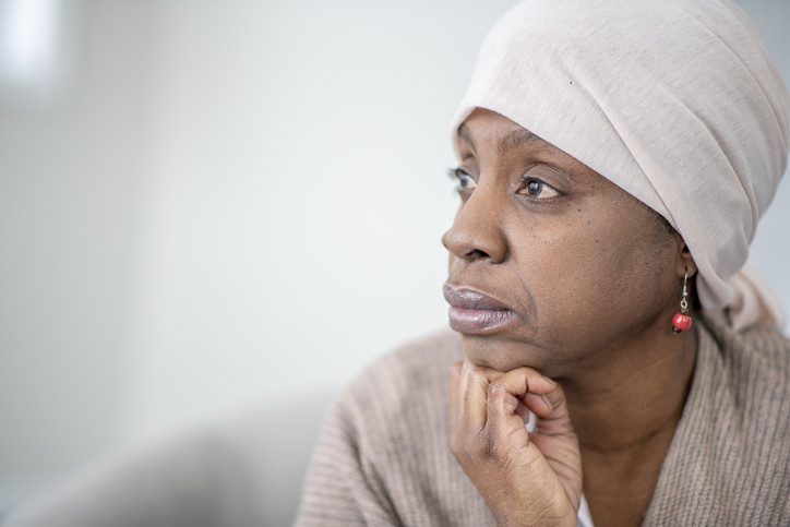 Woman wearing white headscarf looking away in the distance, chin on hand