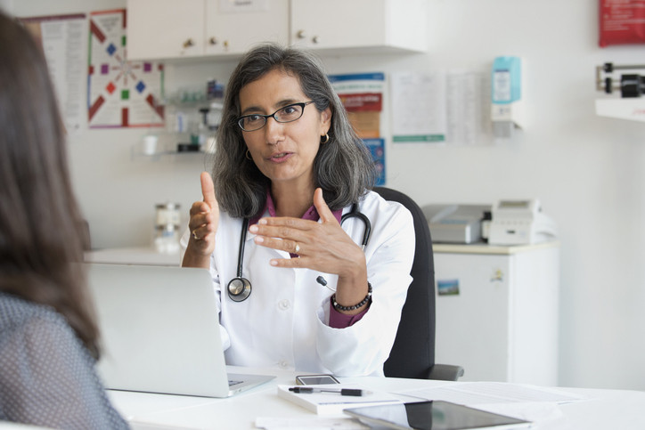 Une femme médecin discutant des soins avec une femme dans un bureau de soins de santé avec des graphiques sur le mur
