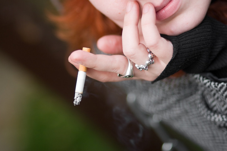 Girl with silver rings with cigarette in hand.