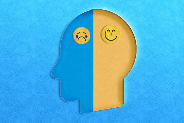 illustration en papier découpé montrant une tête de profil avec une moitié bleue avec un visage de type emoji qui pleure et l'autre moitié jaune avec un visage heureux