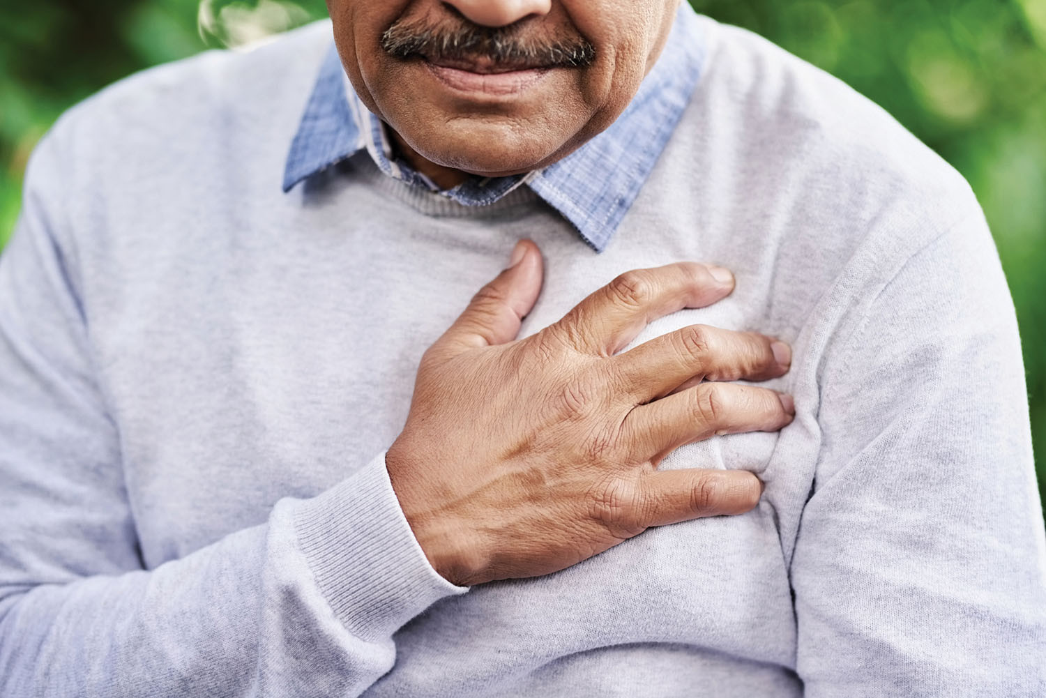 photo of an older man clutching his chest experiencing pain