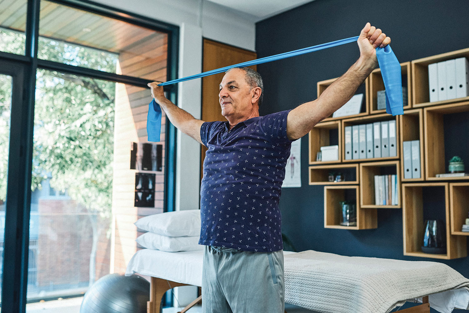 photo of a mature man exercising at home using rubber exercise bands
