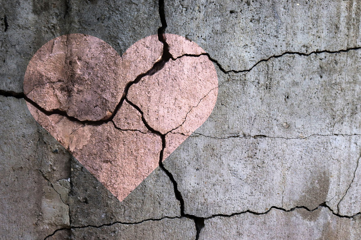 A pink heart on sagging cracked concrete;  broken heart concept 