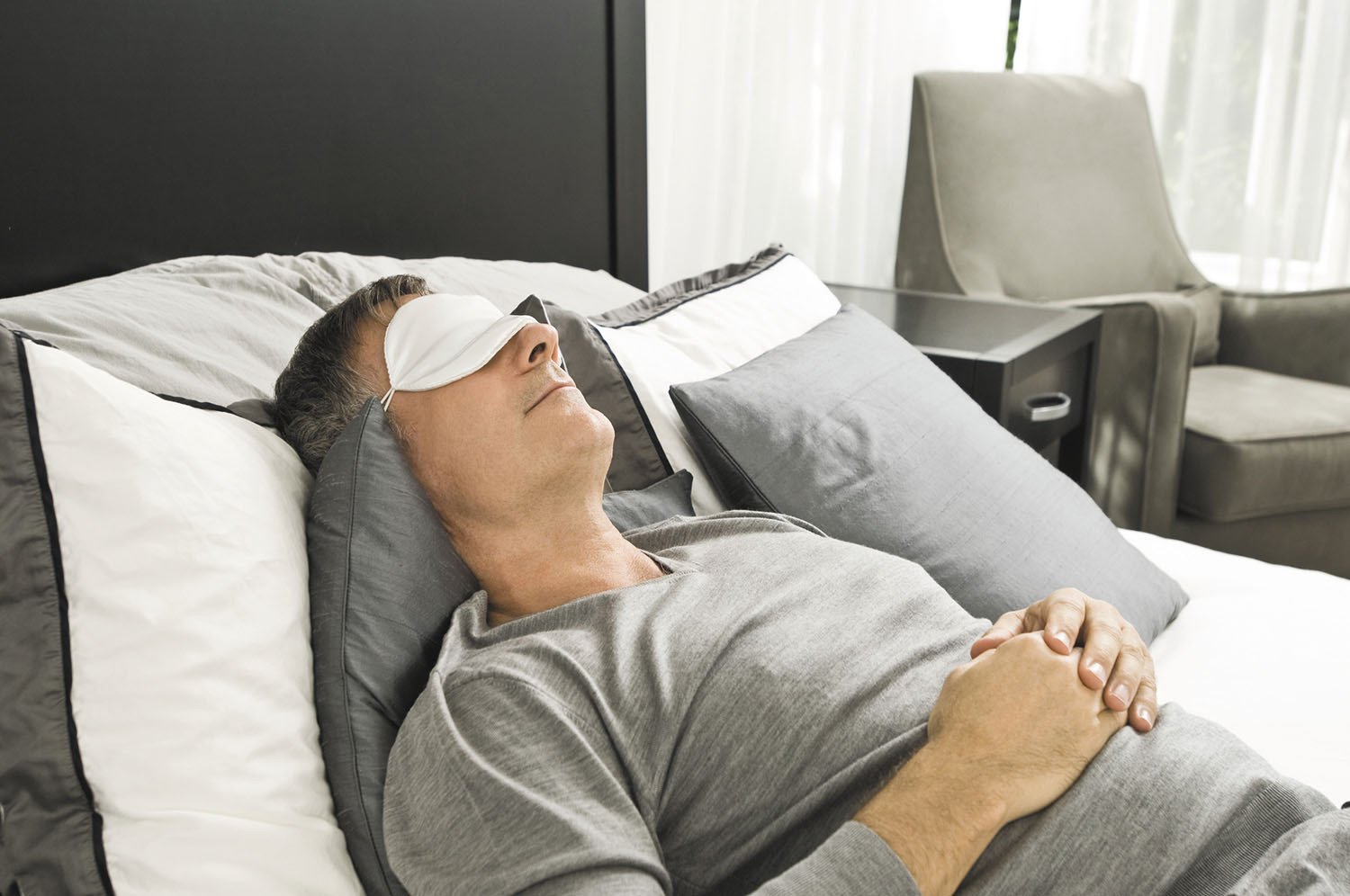 photo of a man in bed on his back wearing a sleep mask