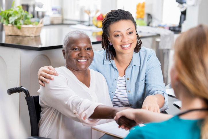 photo of an older woman and her daughter at home talking with a nurse