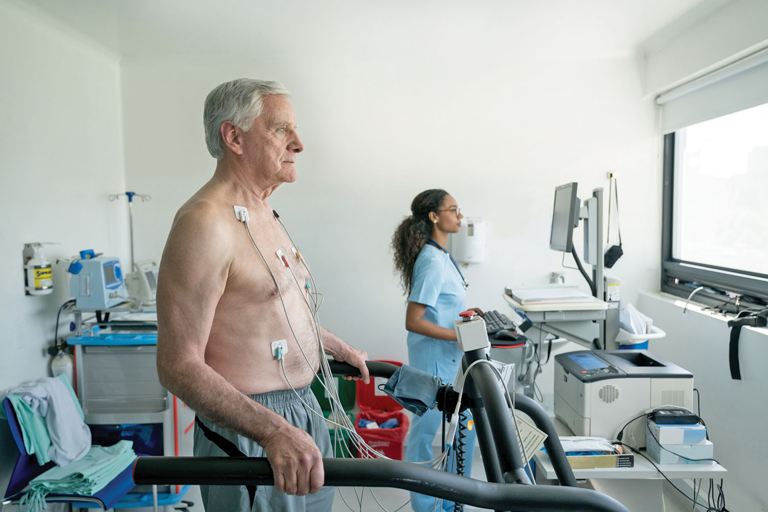 photo of a senior man undergoing a heart stress test with the technician in the background