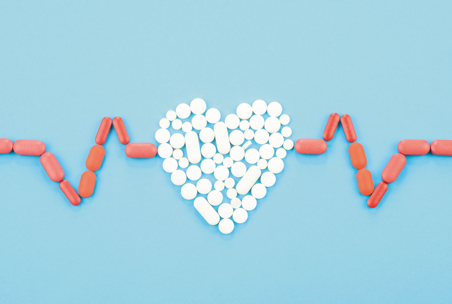 illustration using pills to form a heartbeat line in red and a heart in white in the middle