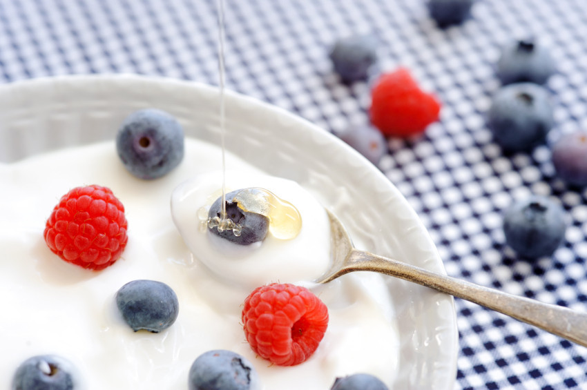 A photo of a bowl of plain yogurt topped with raspberries and blueberries. 