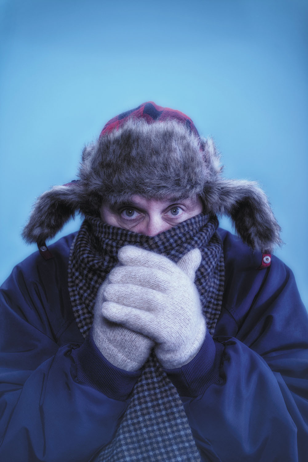 photo of a man bundled up in a parka, scarf, fur lined hat, and gloves