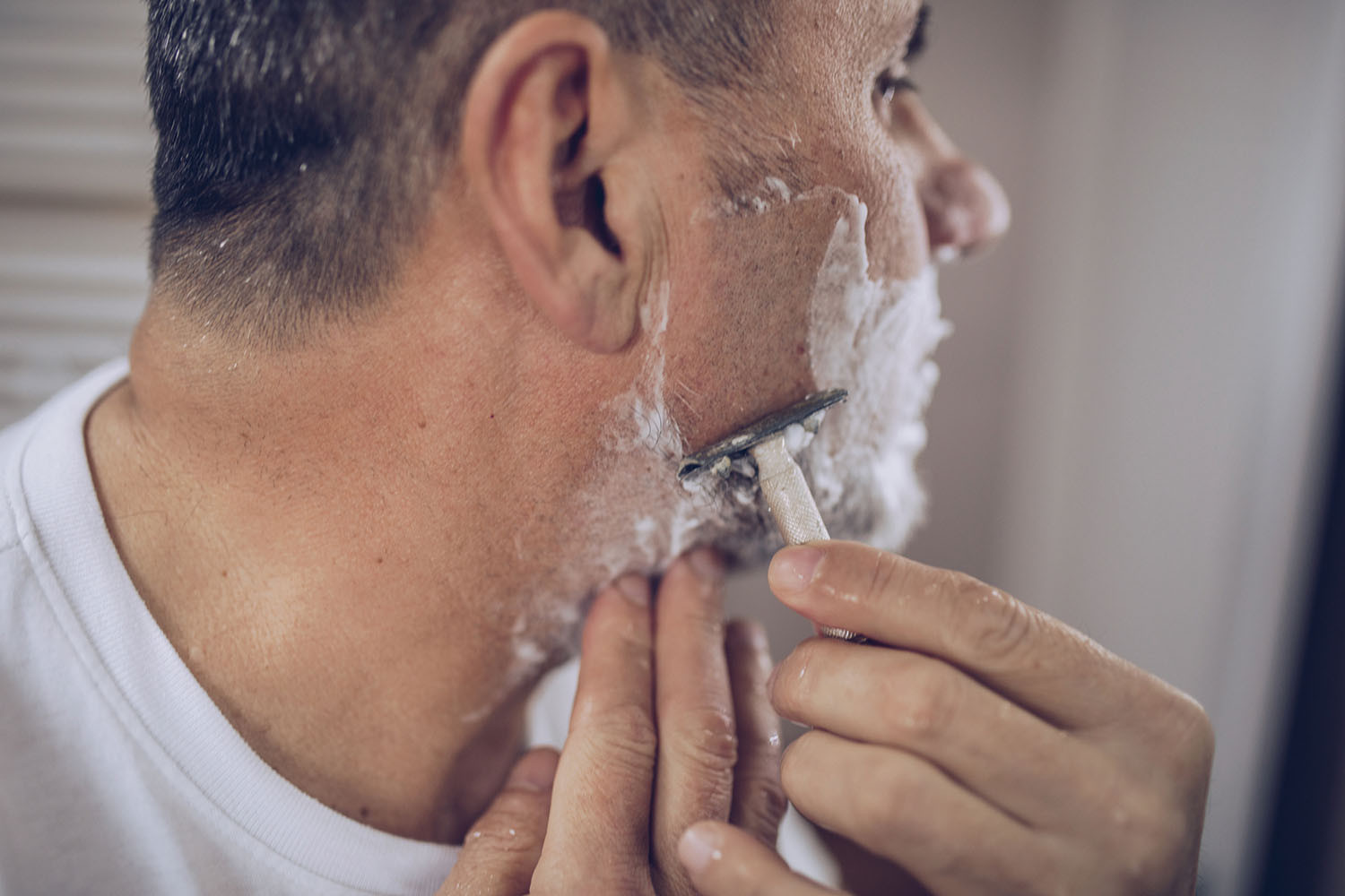 фотография мужчины, брящегося с помощью безопасной бритвы