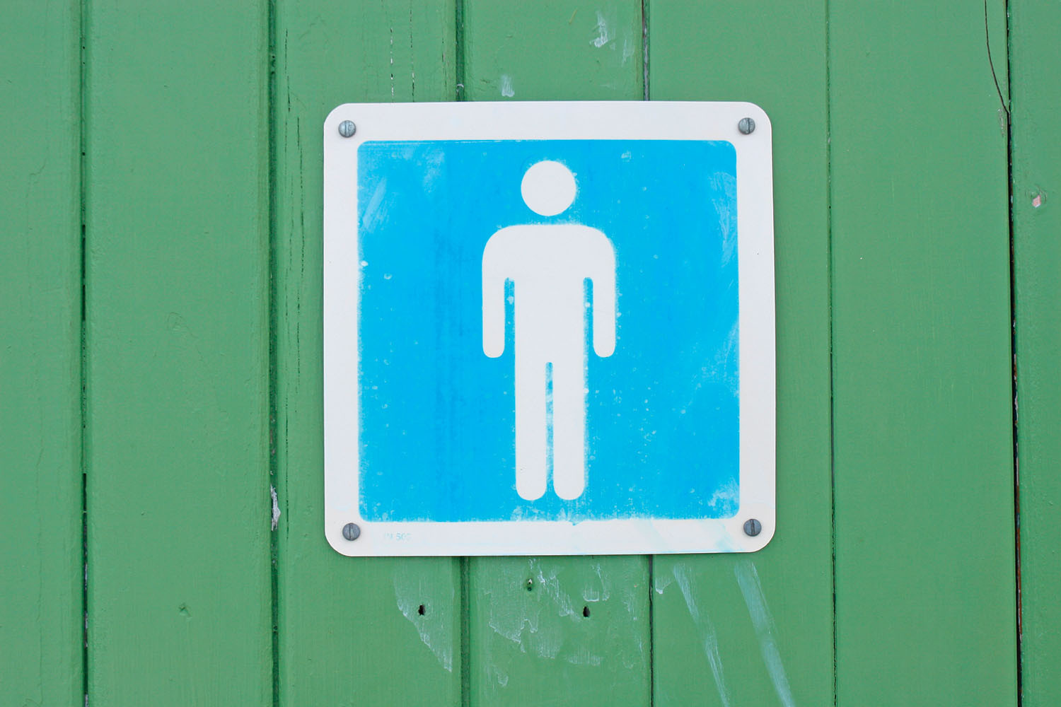 photo of a sign with the men's room symbol, printed in blue, and hung on a wall painted green