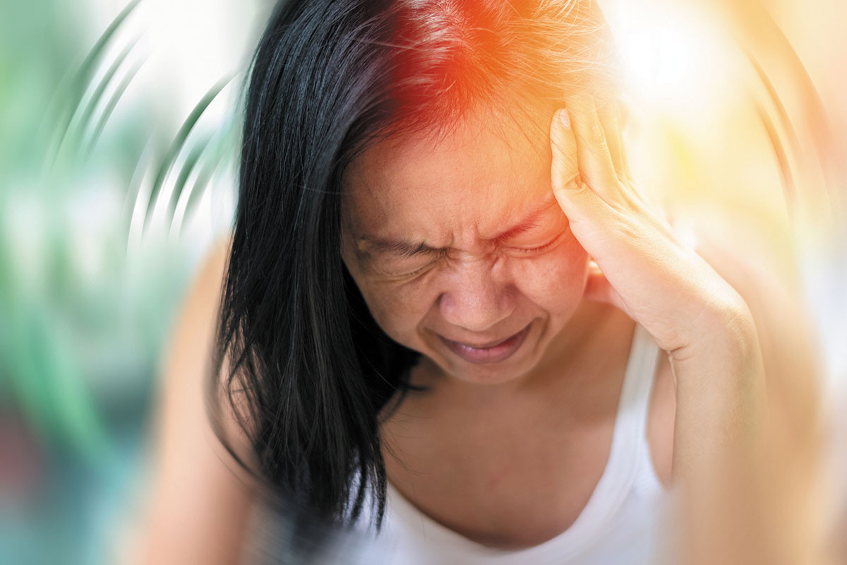 photo of a woman holding her hand to her head reacting to headache pain