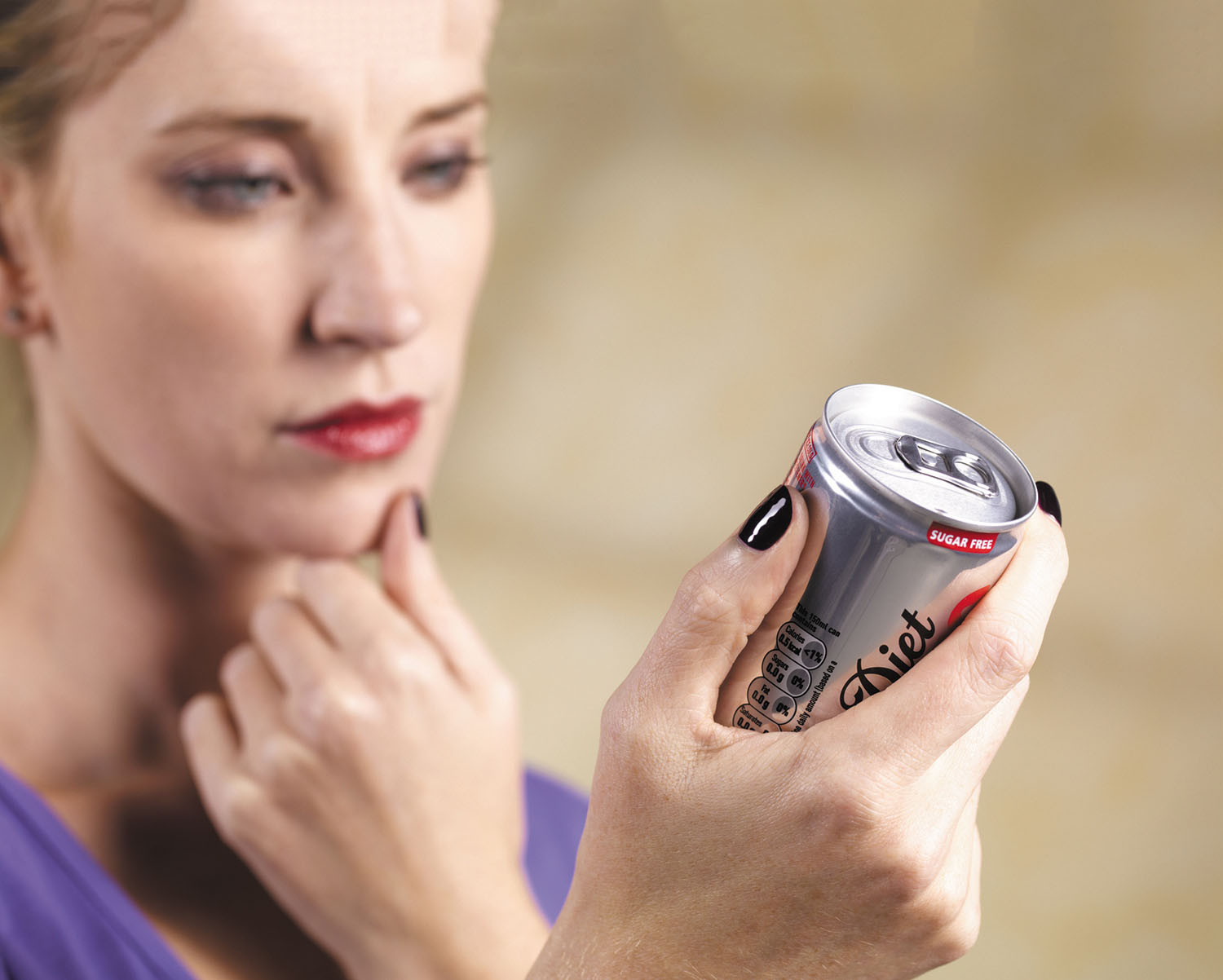 photo of a woman holding a soda can and reading the label