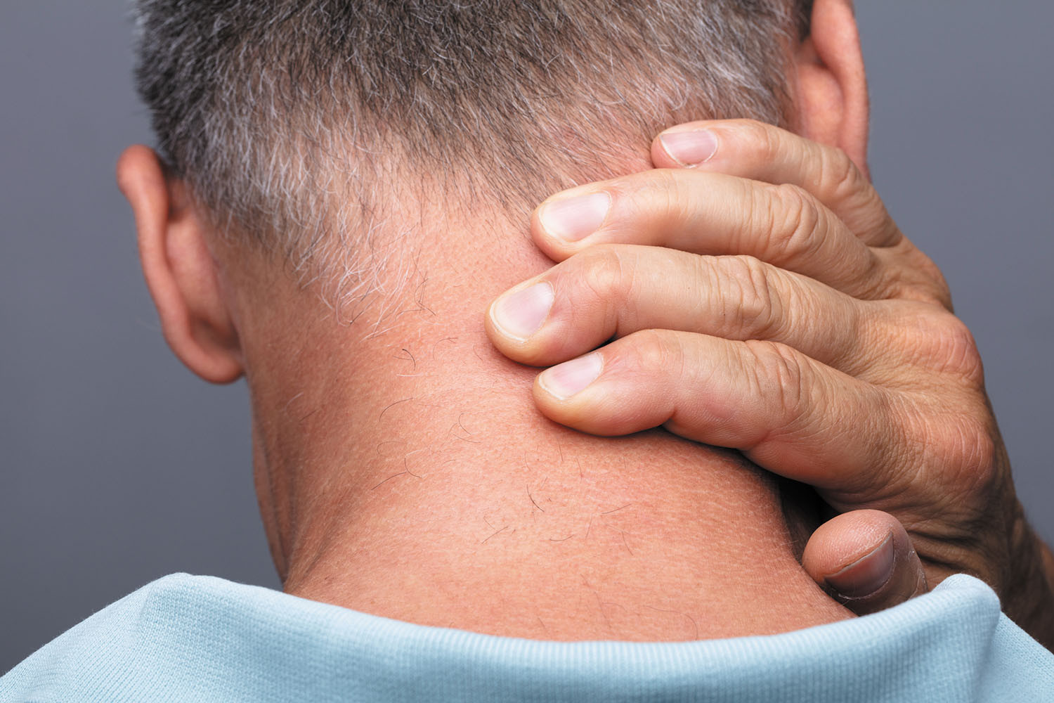 photo of the back of a man's head; he is holding his right hand on it due to pain