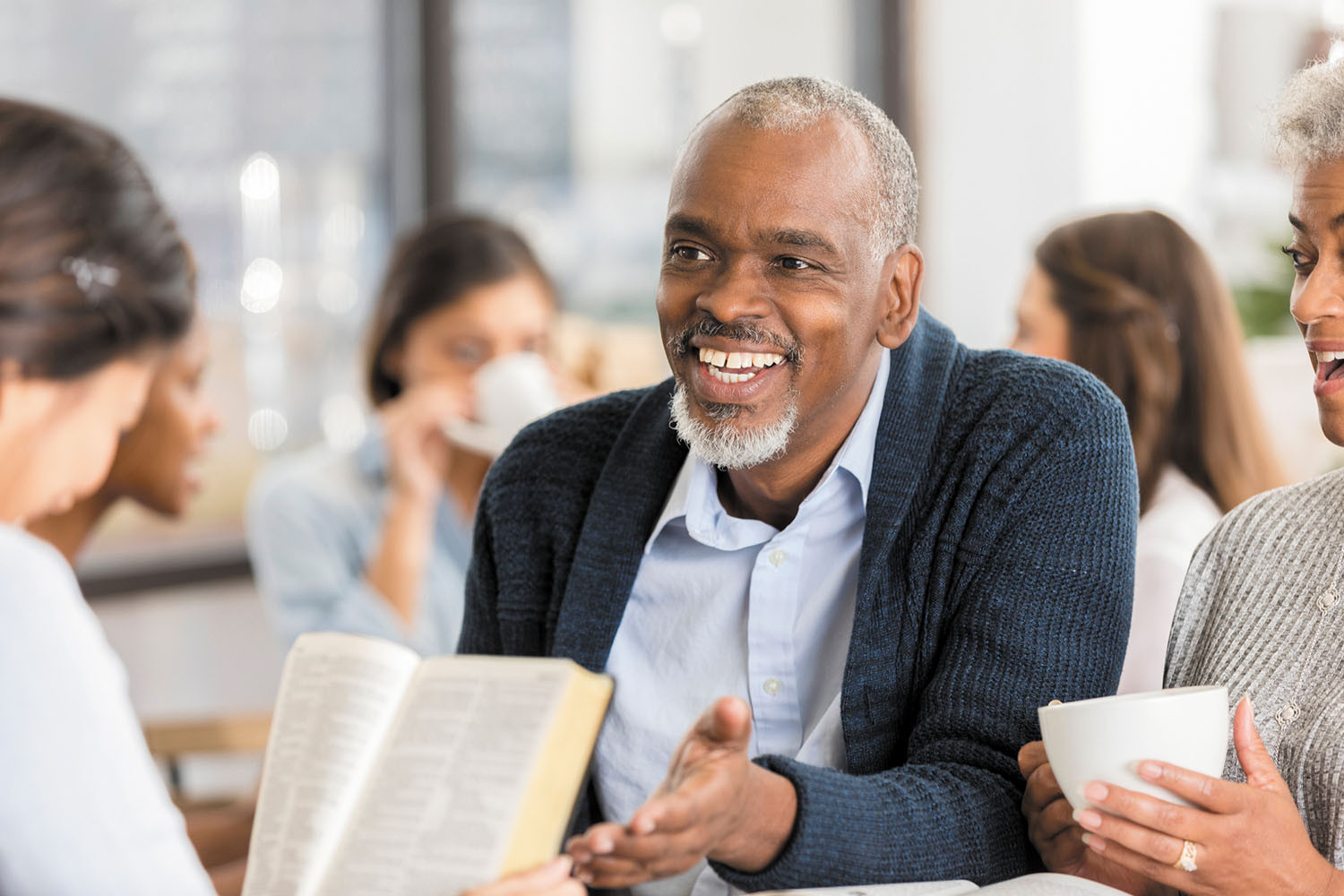 photo of a smiling senior man sitting among a group of people in a bible study class