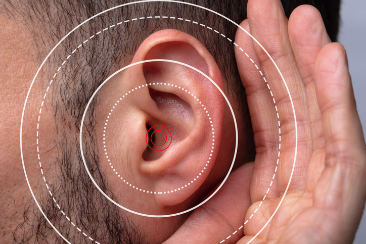 A close up of a man cupping a hand behind his ear with white and red circles indicating sound waves; concept is trouble hearing