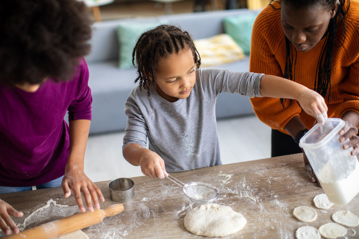 A young boy working with dough to bake with his parents