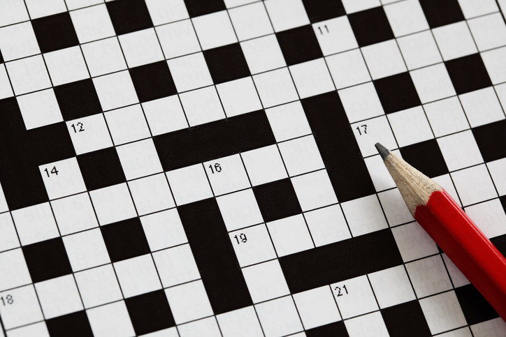 A black-and-white crossword puzzle grid and a red pencil