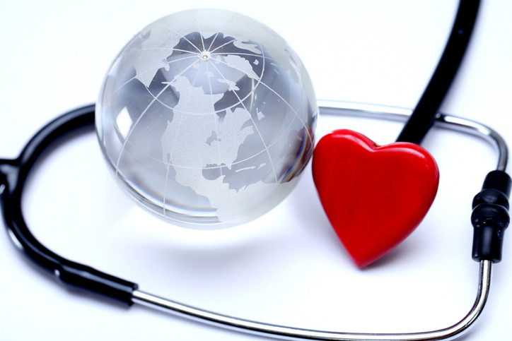 A crystal globe with countries etched on, circled by a stethoscope with a red heart;  Earth health and our health connect