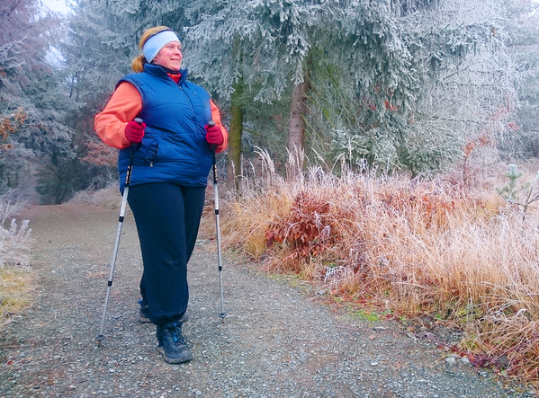 Woman dressed warmly in layers and walking in a cold landscape using Nordic poles