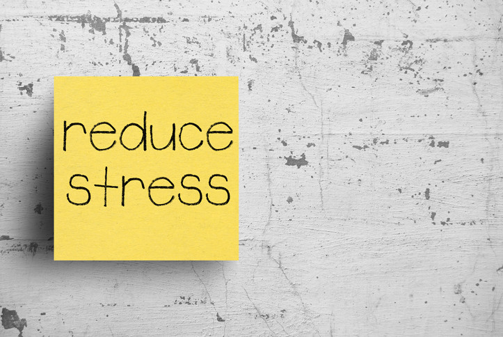Photo of sticky note on wall that says 'reduce stress'