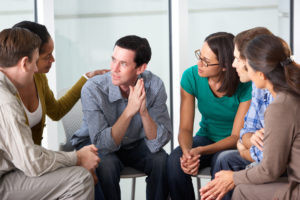 A group therapy session, one man is talking while the rest of the group listens