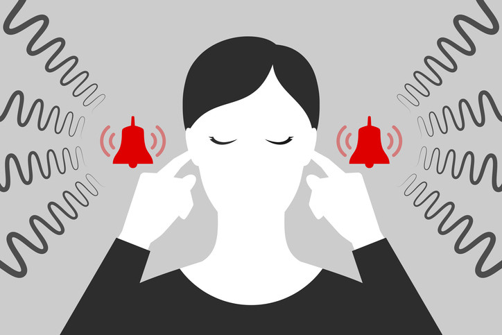 A graphic of a woman plugging her ears. Next to both of her ears, bells are ringing and emitting larger sound waves