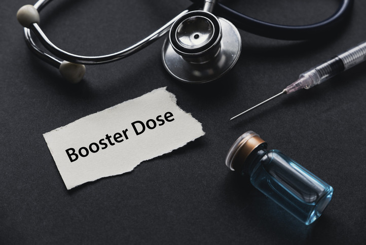 Photo of stethoscope, syringe, vaccine vial, and the words "Booster Dose" on black background