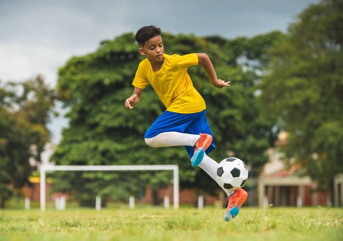 Boy playing soccer on grass field