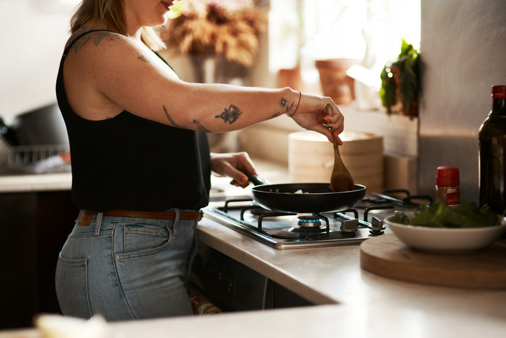 A woman cooking on the stove, stirring food in a pan