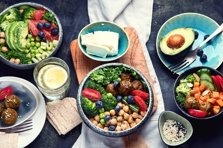 A table spread with bowls full of vegetables, fruits, beans, and other proteins; healthy food choices