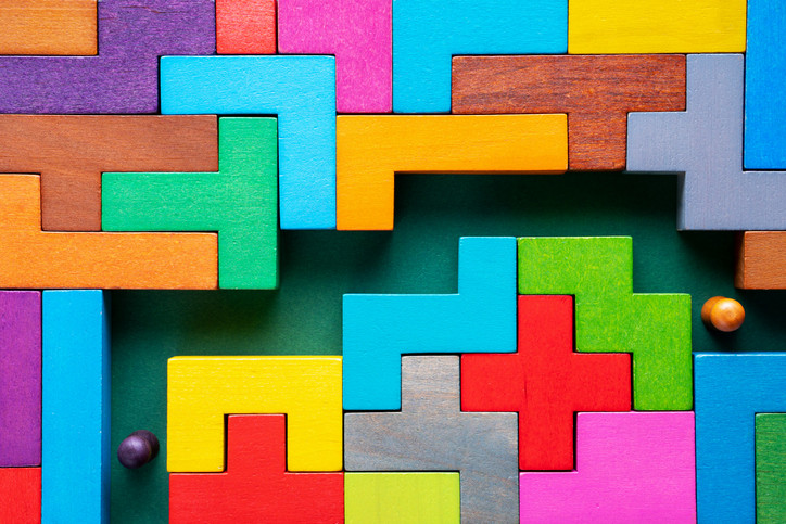 Colorful blocks locked together in a maze. Two figures are finding their way through obstacles; concept of resilience. 