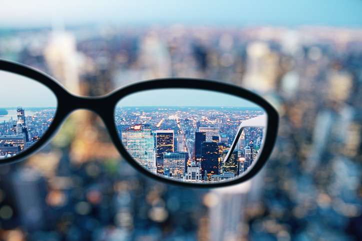 The view of a city from a high-rise, most of it is blurry except for what can be seen within the lenses of a pair of classes