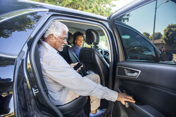 photo of a senior man reaching to close the door after getting into the back seat of a rideshare car