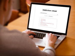 Man searching for addiction rehab on his laptop