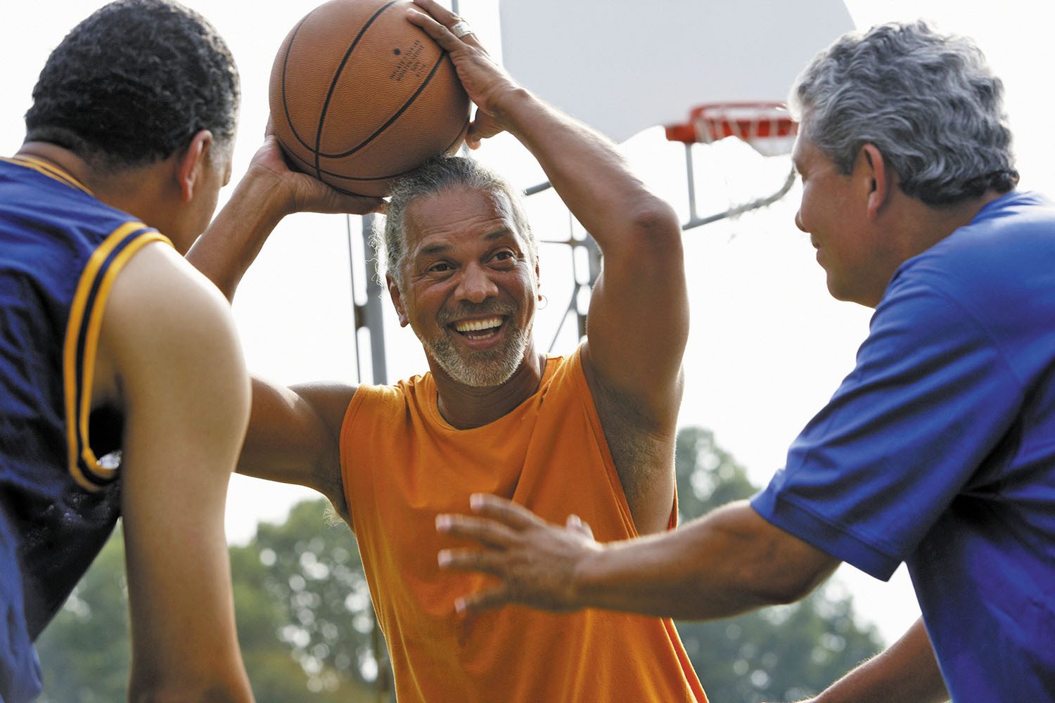 photo of three older men playing basketball outdoors