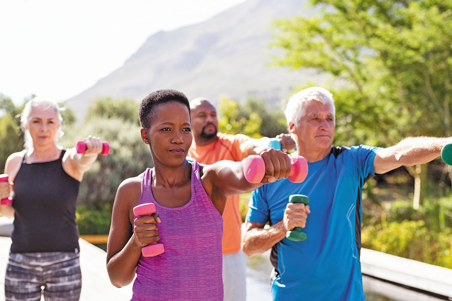 A group of people exercising outdoors with light weights. 