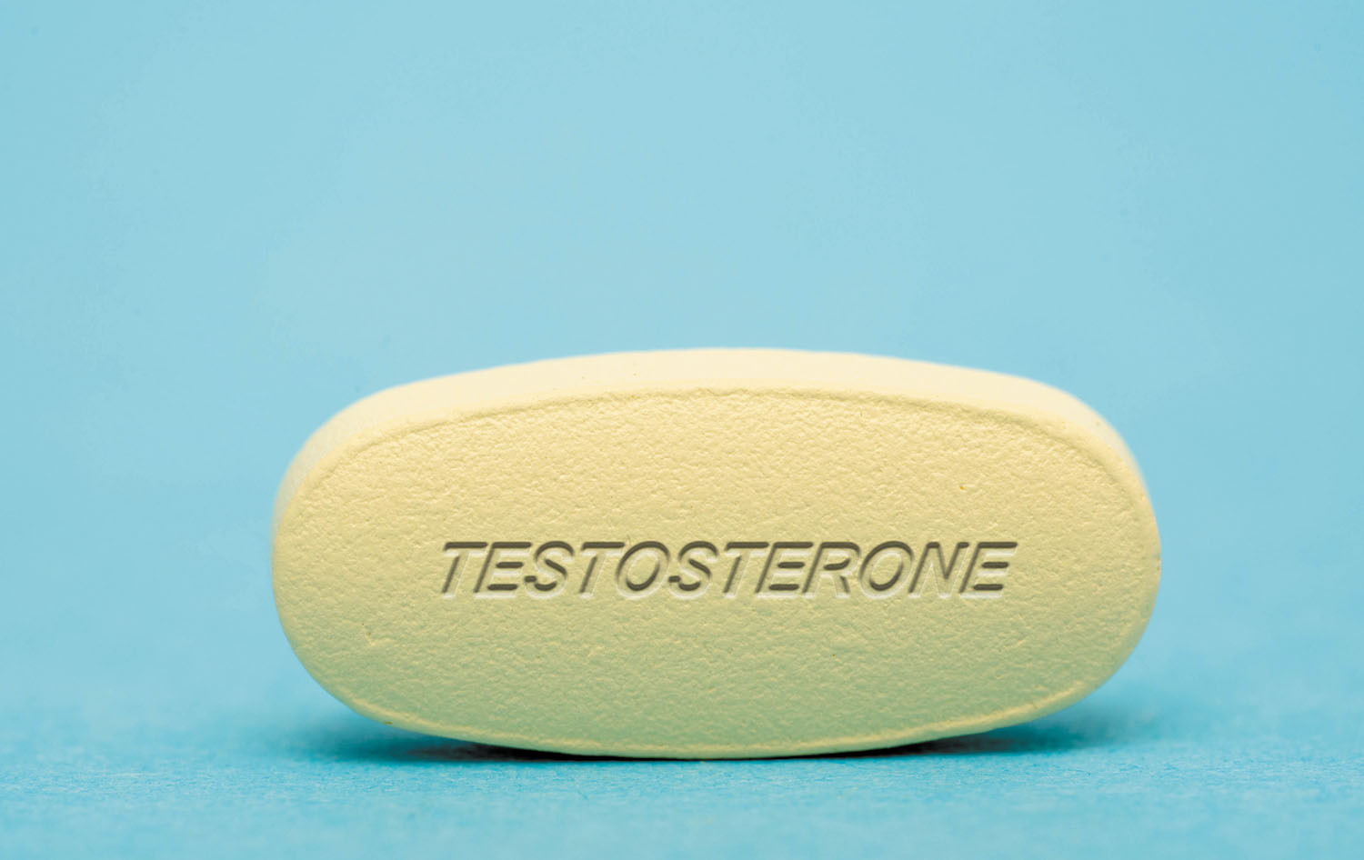 photo of a pale yellow pill against a blue background stamped with the word testosterone