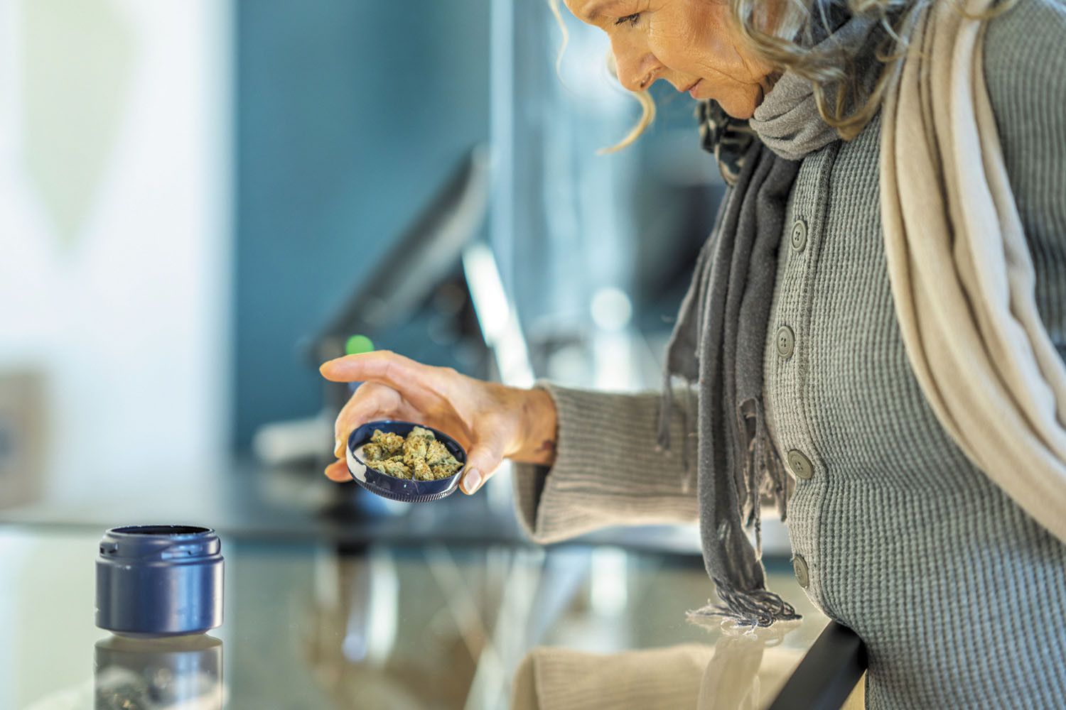 photo of an older woman at a counter in a marijuana dispensary examining the product