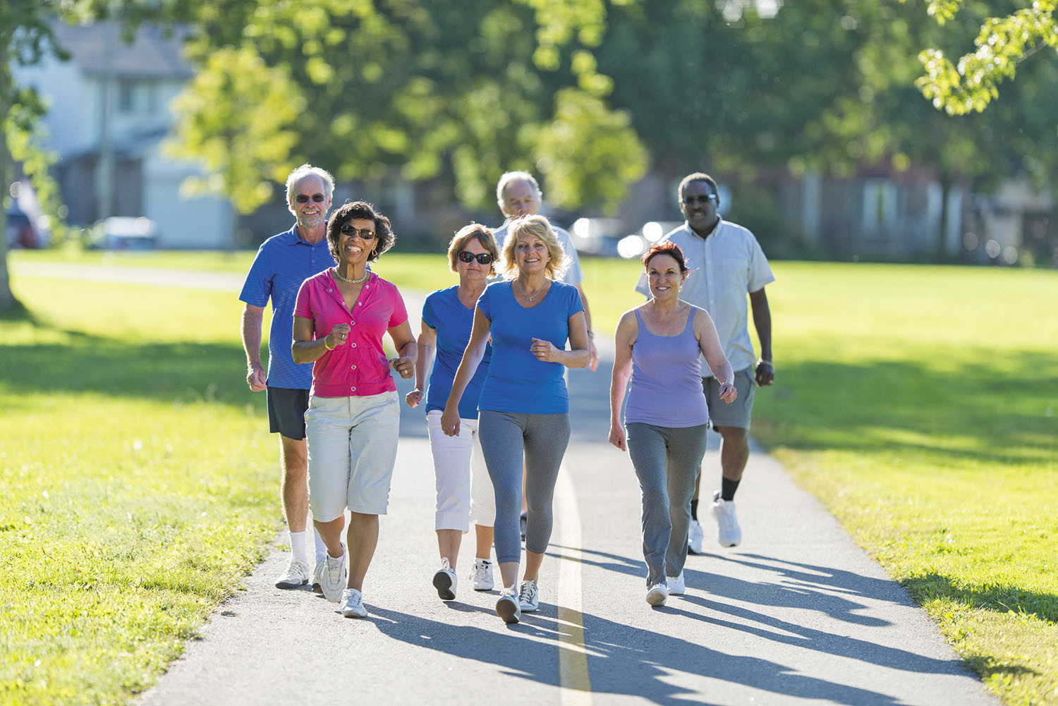 photo of a group of seven older adults fast-walking on a paved path in a park