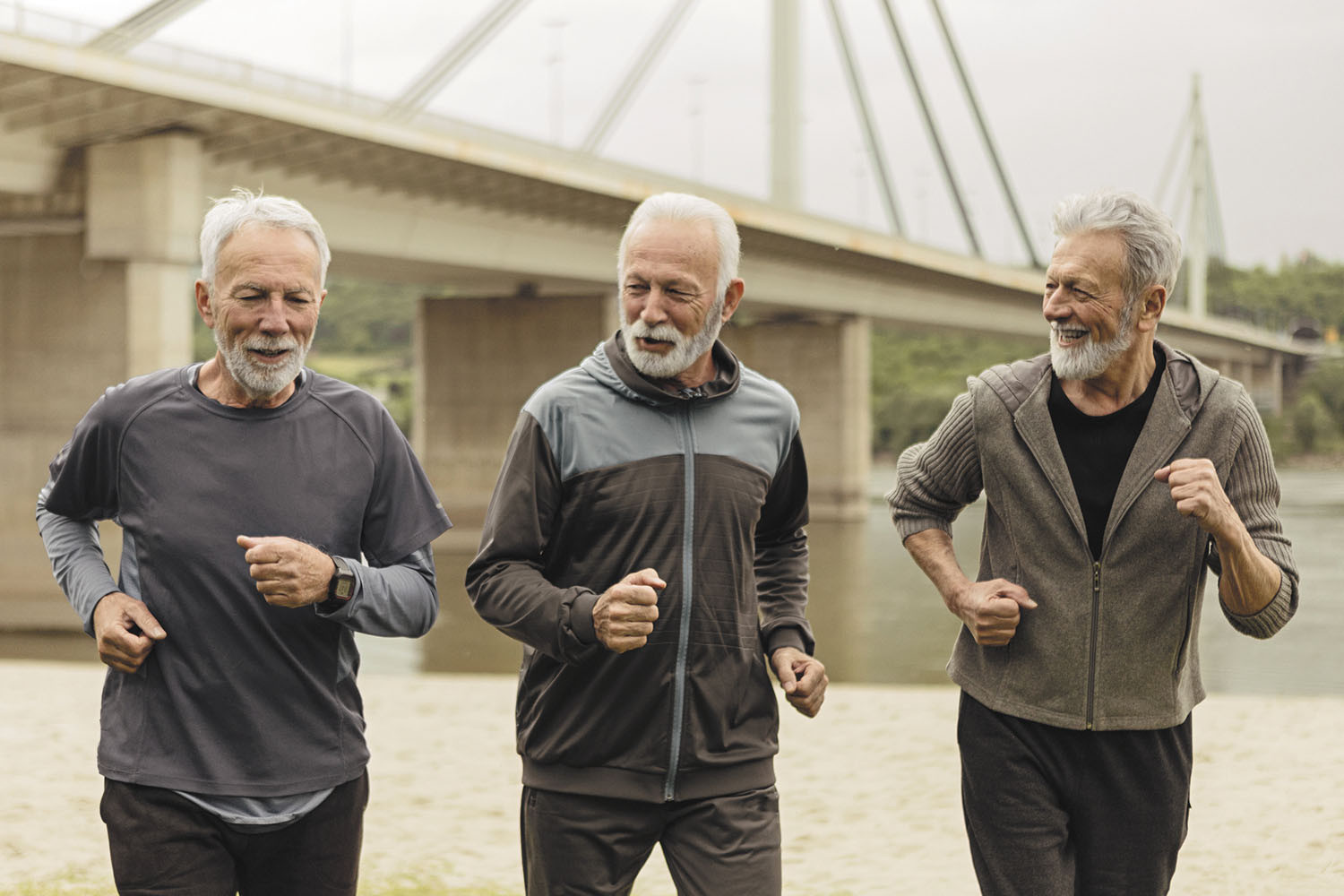 photo of three mature men fast-walking past a bridge in the background