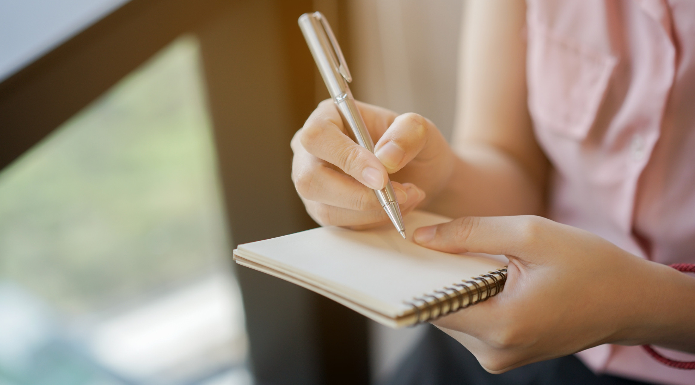 woman's without face visible writing a list with a pen and paper