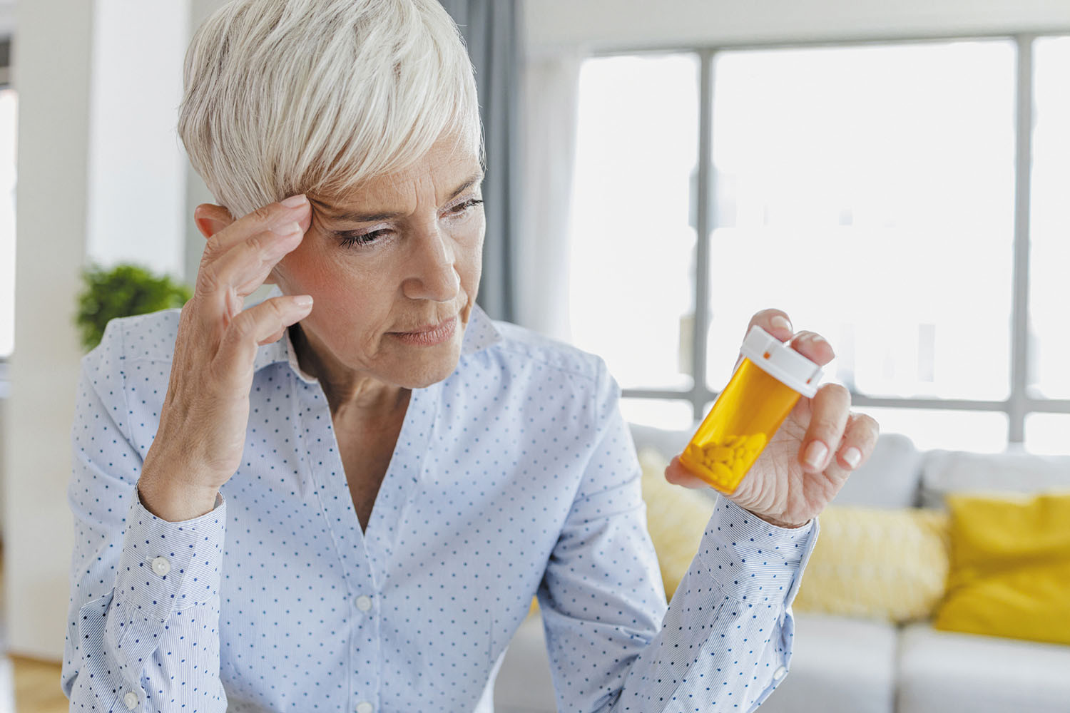 photo of a mature woman looking at a bottle of prescription pills
