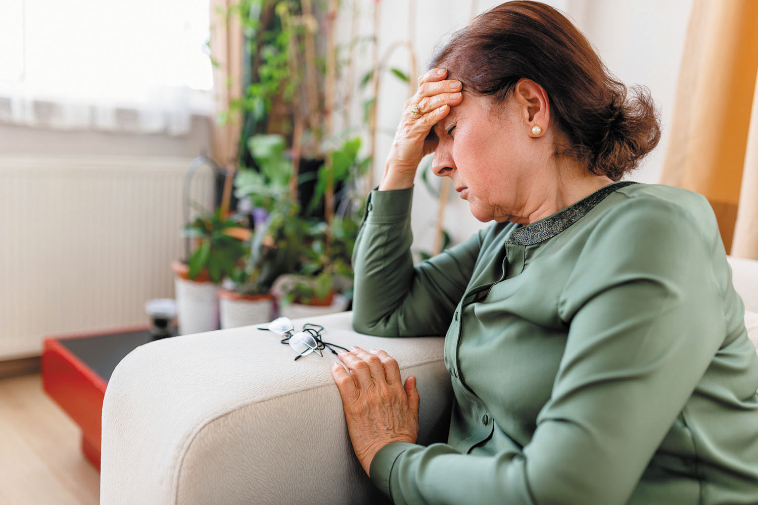 photo of a woman experiencing fatigue sitting down holding her right hand to her forehead