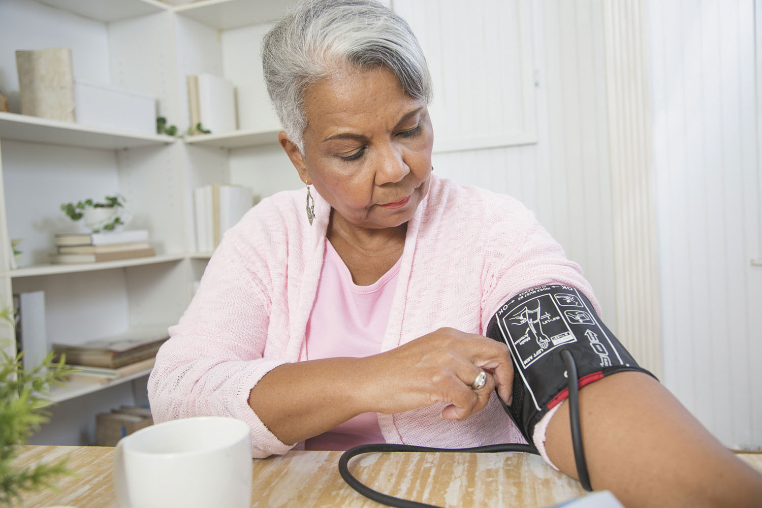 photo of a senior woman taking her blood pressure at home