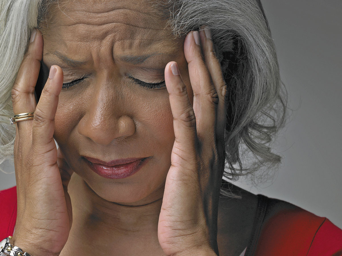 photo of a woman experiencing headache pain holding her hands to the sides of her face
