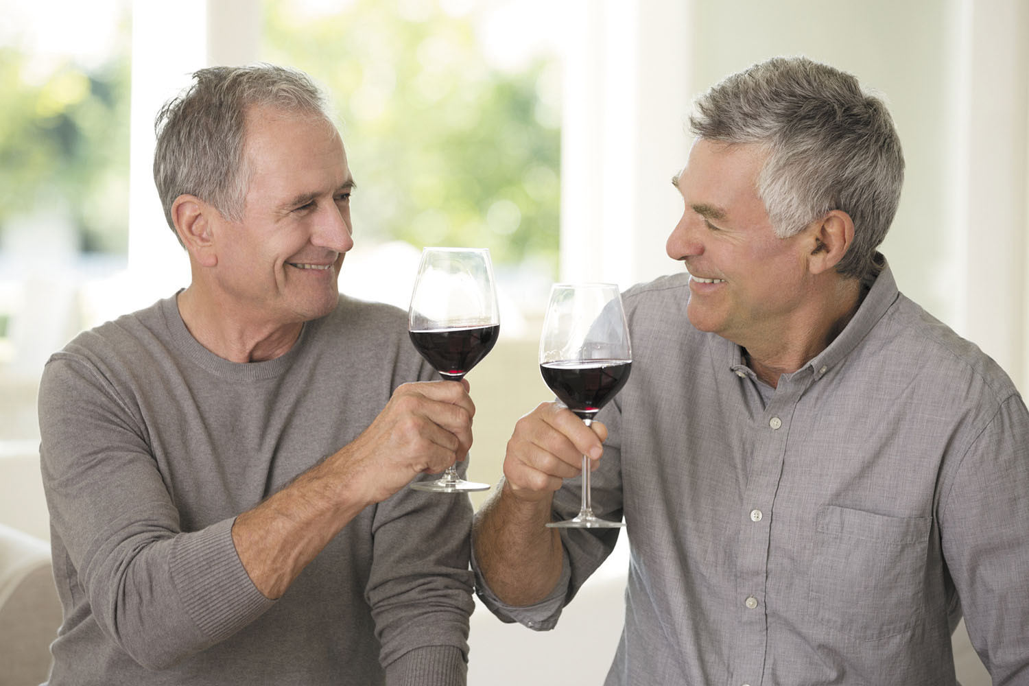 photo of two men smiling and holding glasses of wine